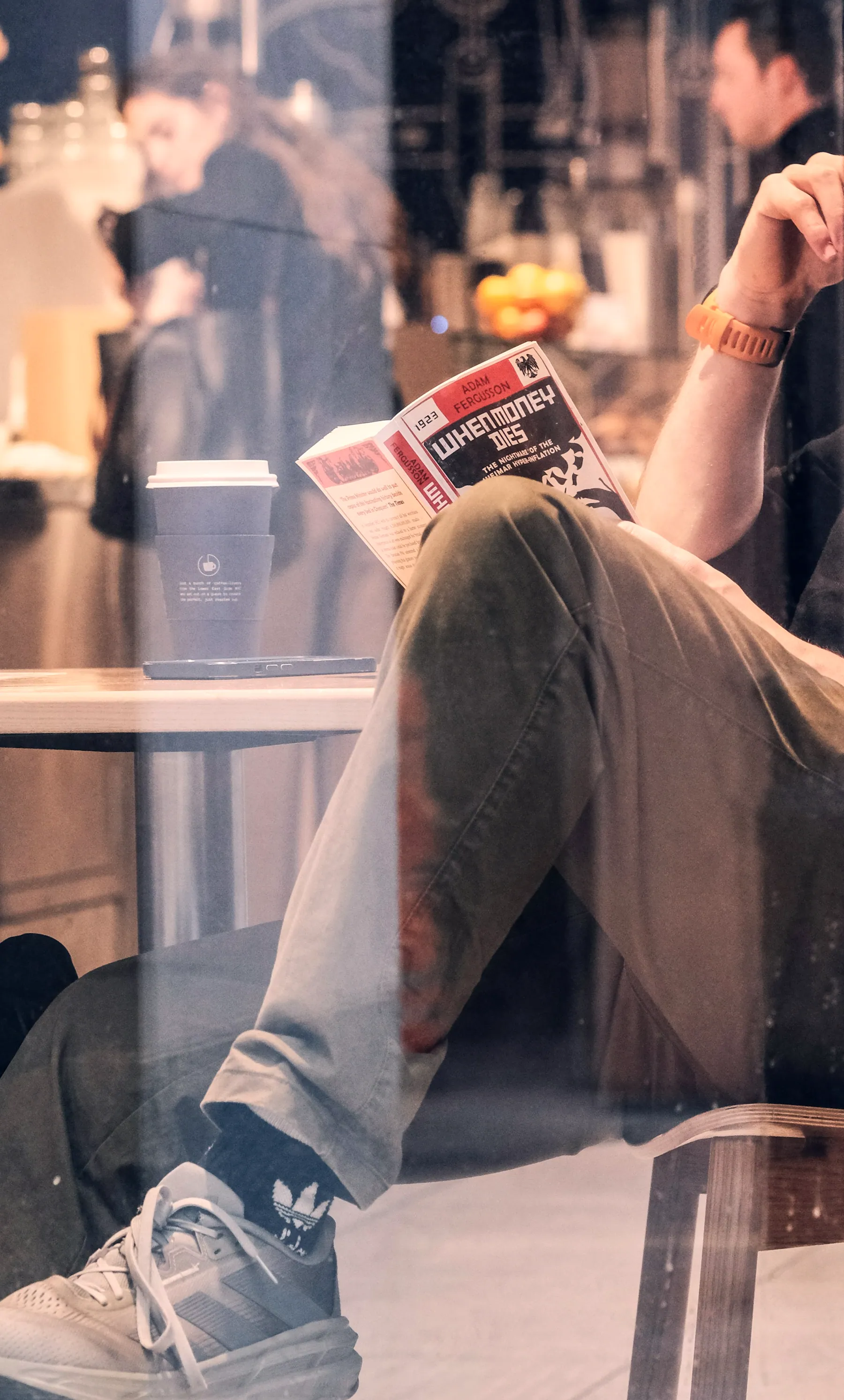 A person reading by a window as the London evening sets in