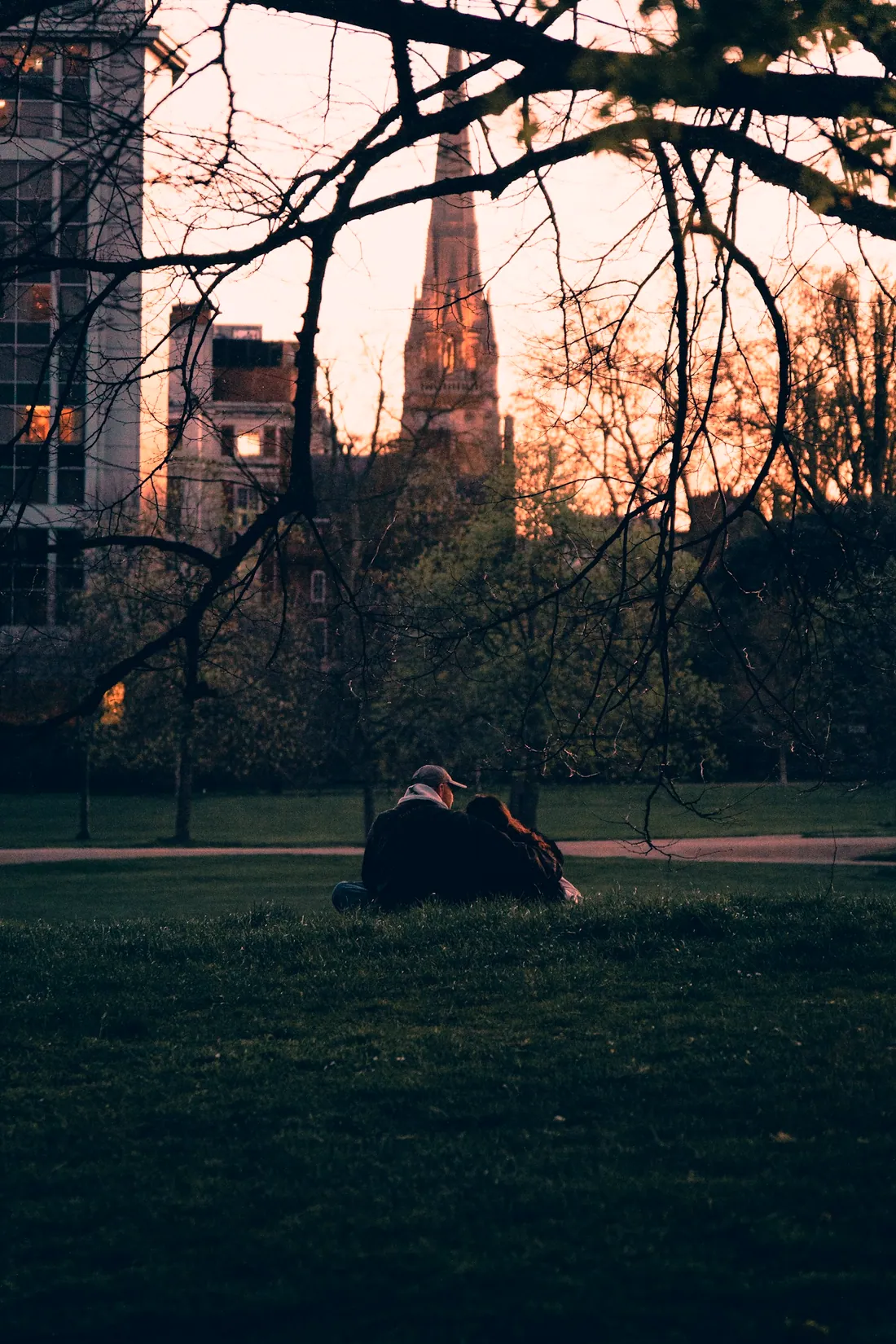 Two people sitting together in a London park at dusk
